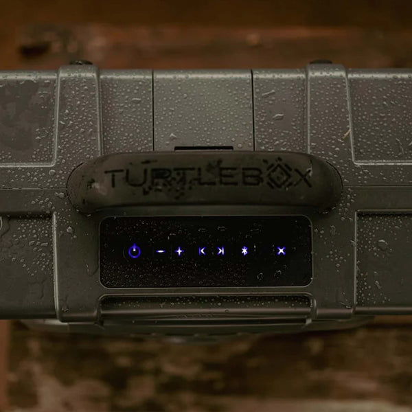detail close up of the top of TurtleBox Gen 3 Gray Portable Speaker with rain drops on it to show the waterproof capability.