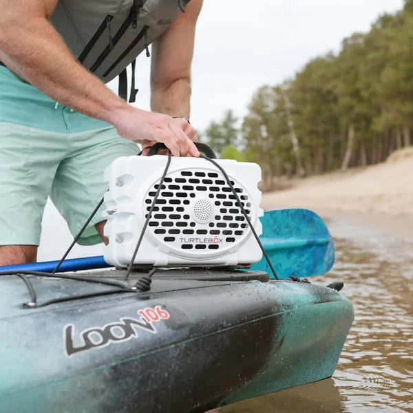 man strapping a TurtleBox Gen 3 White Portable Speaker on top of a kayak.