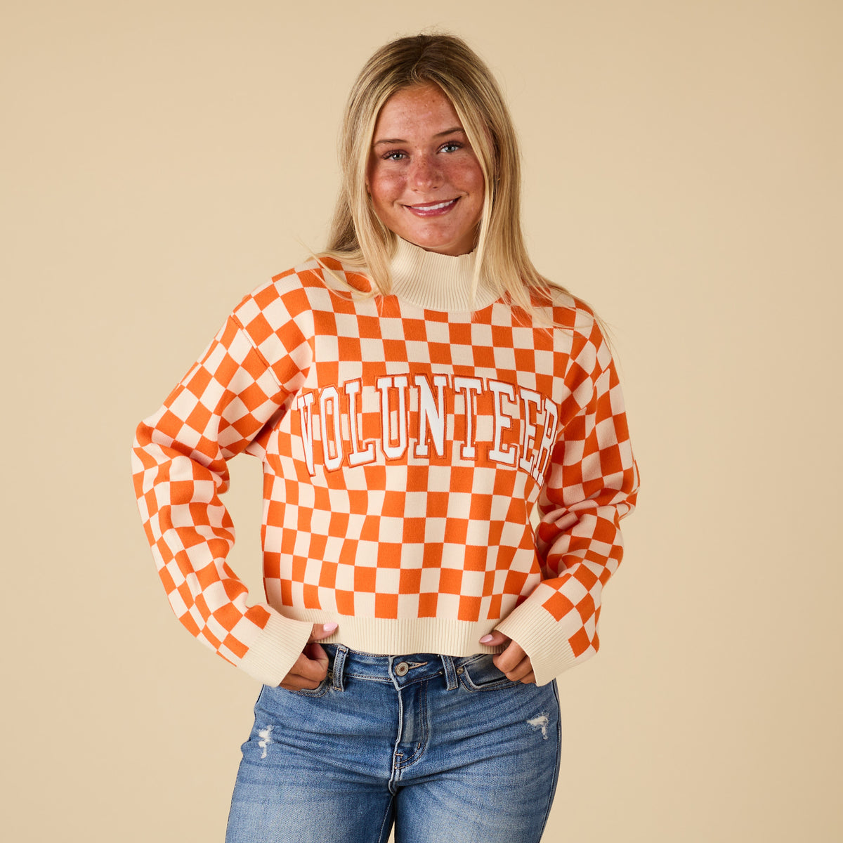 Front view of model wearing Tennessee Volunteers checkered sweater with orange and white pattern and chest lettering.