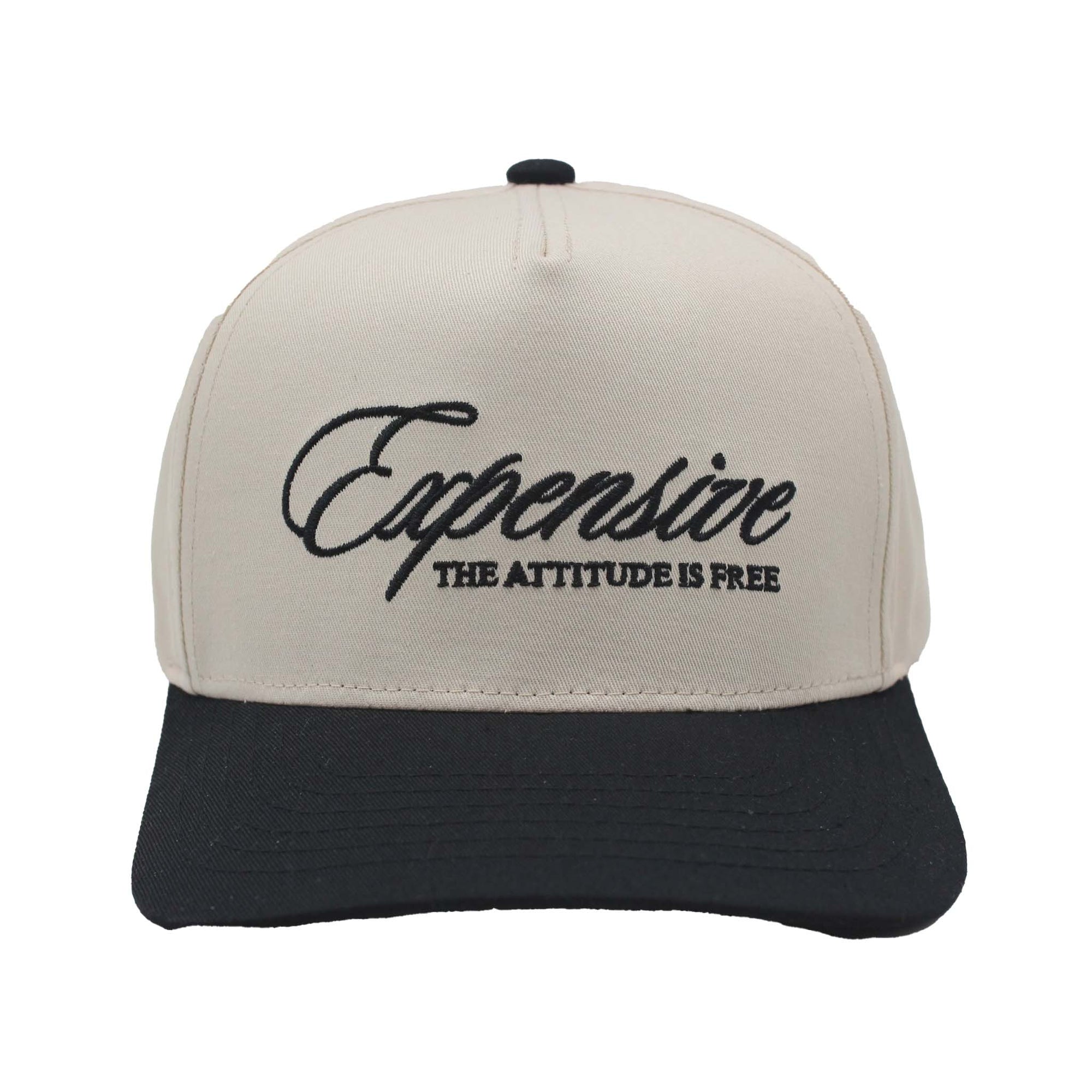 Two-tone trucker hat with natural crown and black bill featuring embroidered text 'Expensive – The Attitude Is Free' on the front panel.