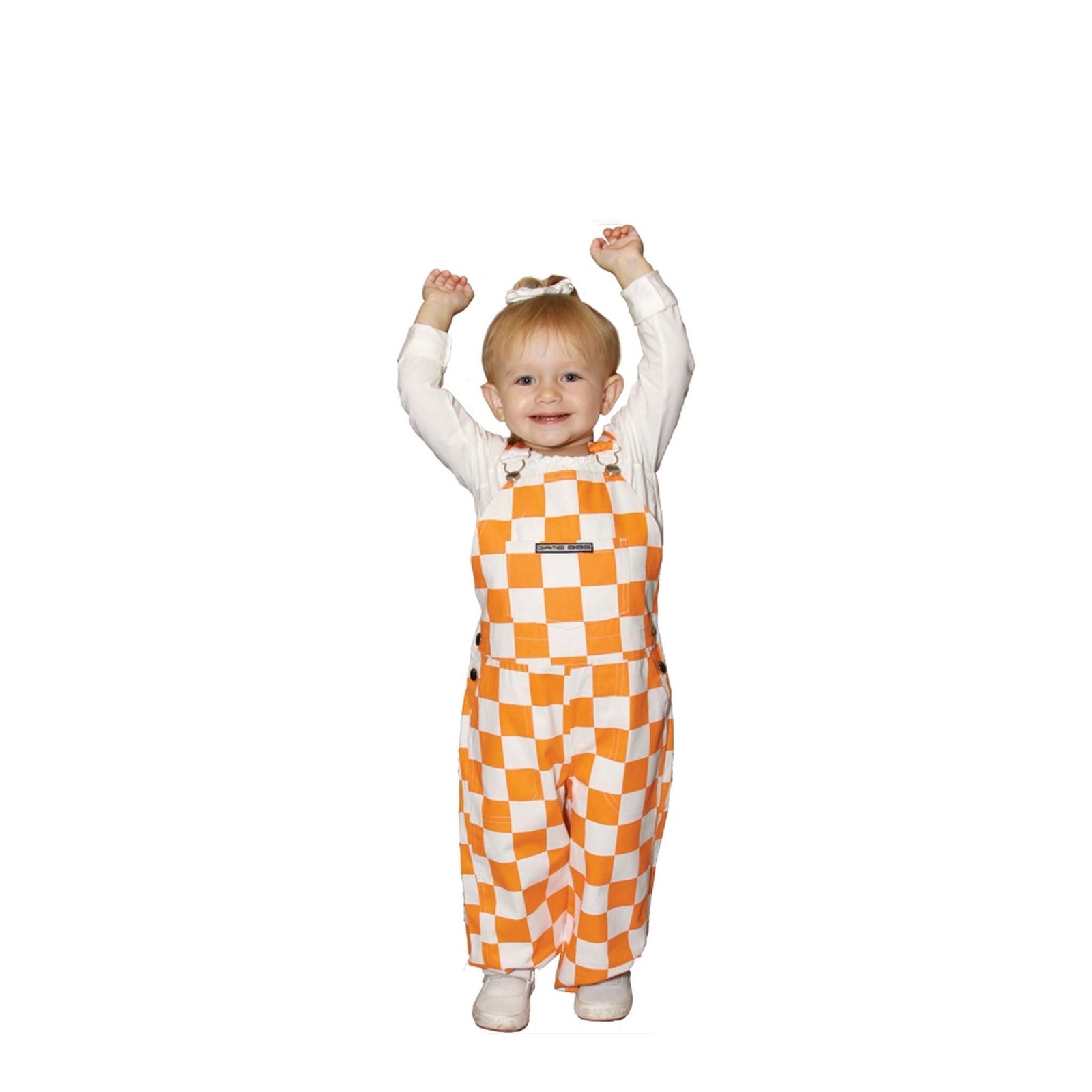 Toddler child wearing orange and white checkered overall bibs with a white shirt and white tennis shoes.