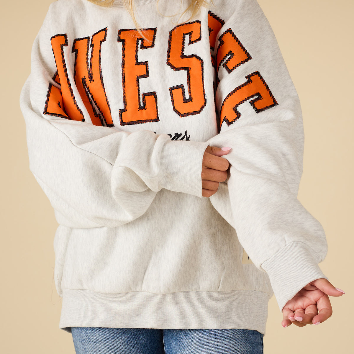 Person wearing a white sweatshirt with orange text on a beige background