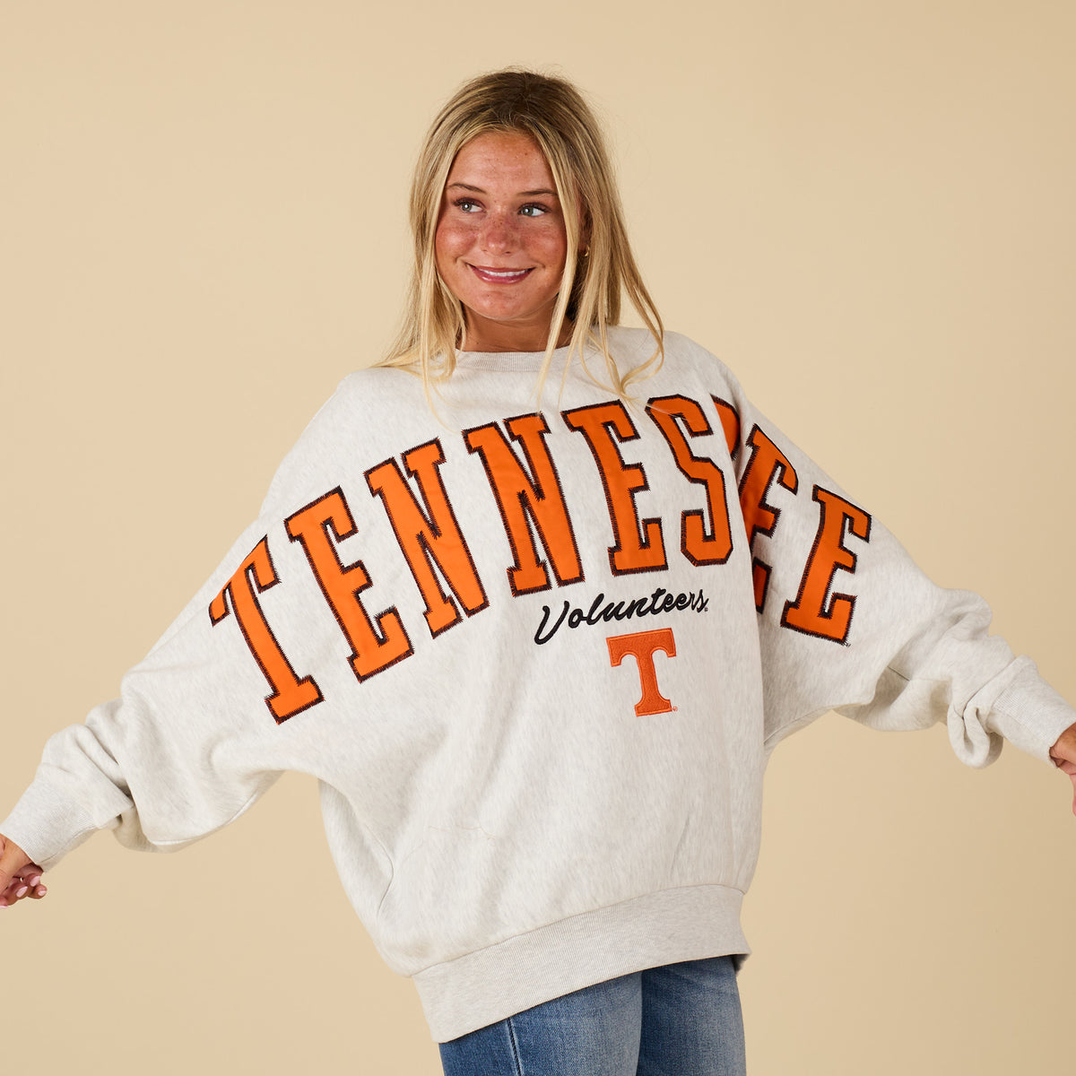 Person wearing a white sweatshirt with 'TENNESSEE Volunteers' embroidered in orange on a beige background
