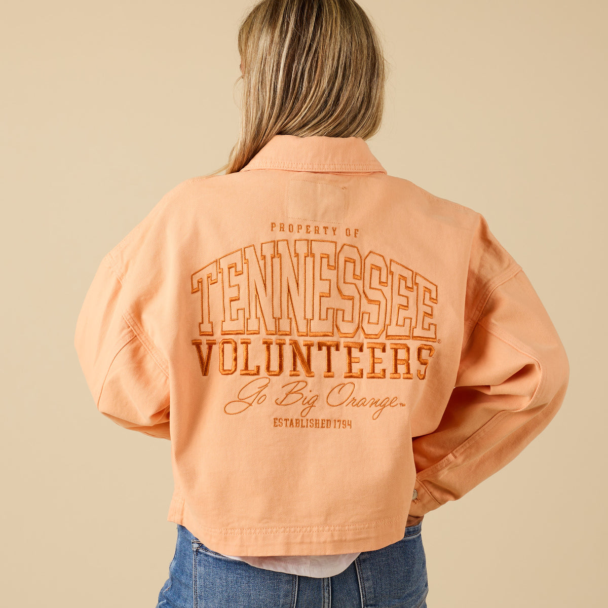 Back of orange cropped jacket with large “Tennessee Volunteers” embroidered design and “Go Big Orange, Established 1794” text.