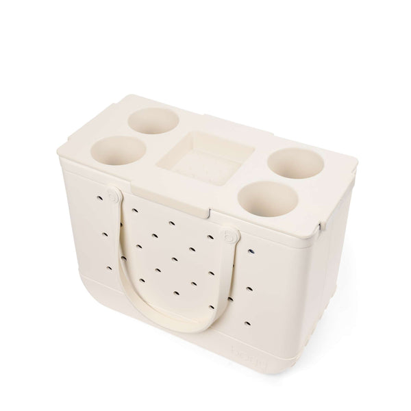 White plastic tray with multiple compartments on top of an off white Bogg Bag shown on a white background