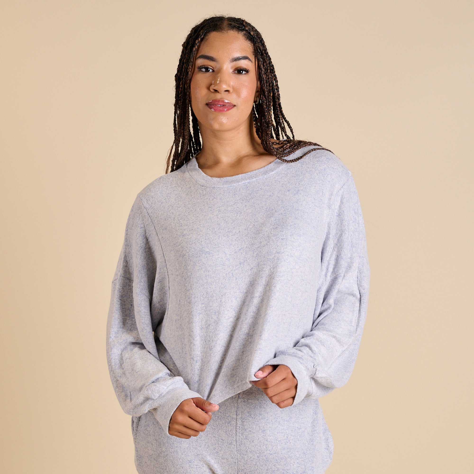 Woman wearing a gray sweater against a beige background