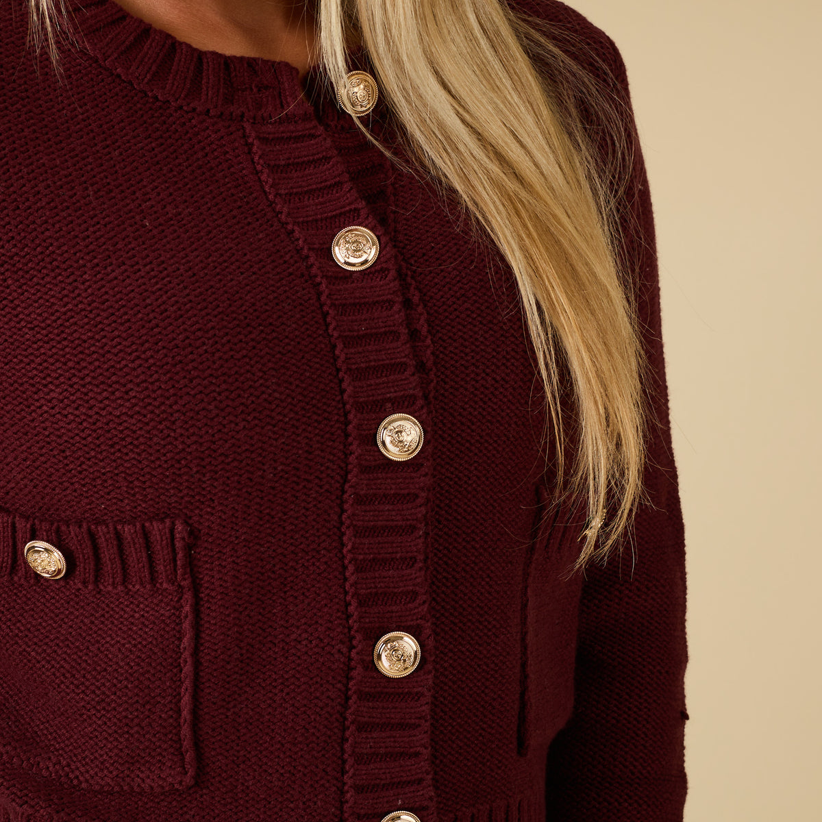 Close-up of redwood cropped cardigan sweater with gold-tone buttons and front patch pocket.