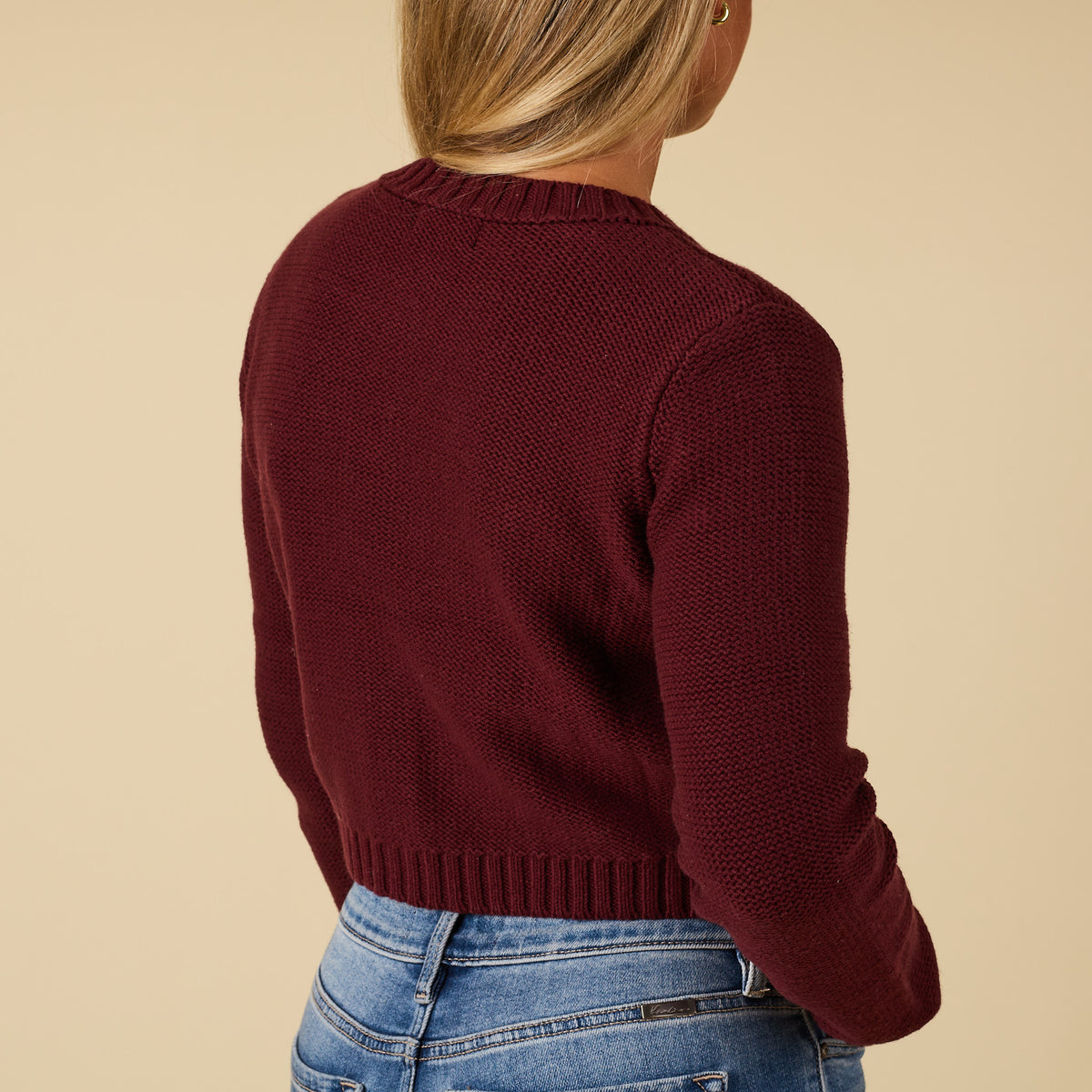 Back view of redwood cropped cardigan sweater with ribbed hem and long sleeves.
