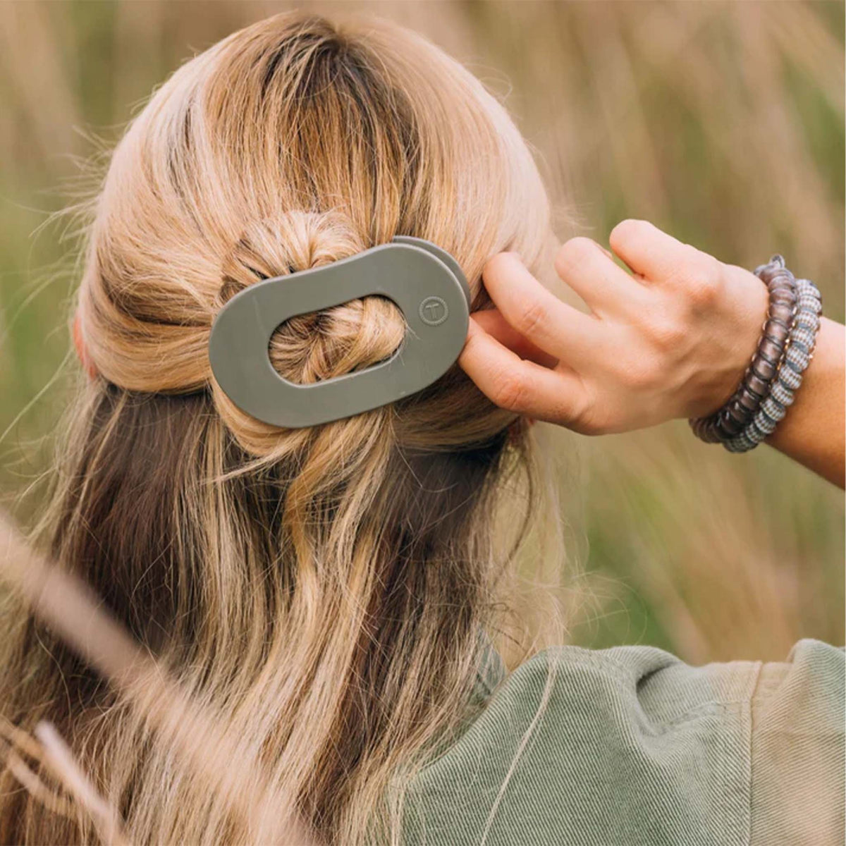 Teleties medium flat oval hair clip in Sage It Ain’t So, shown securing blonde hair in a twisted half-up hairstyle.