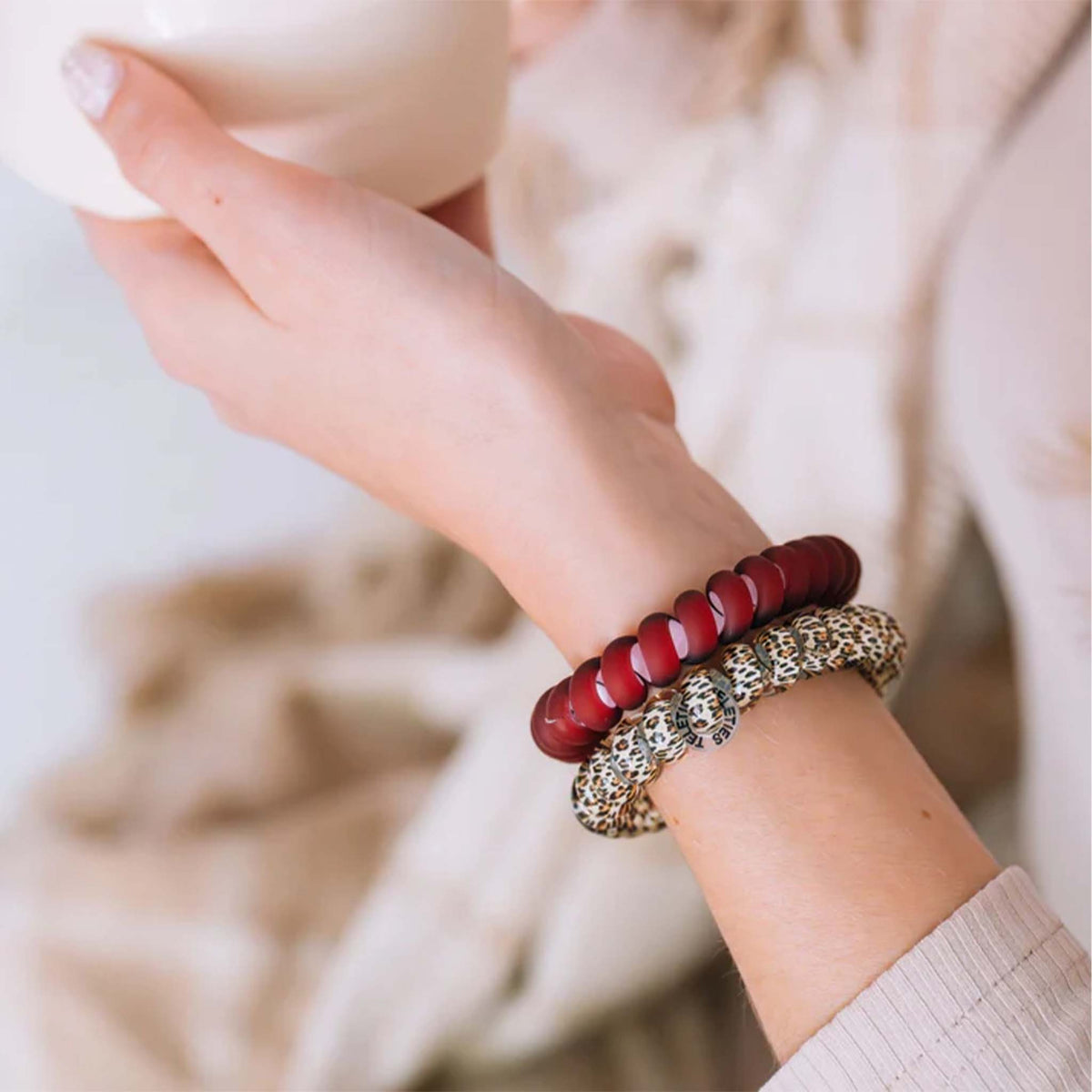 Teleties Large Hair Ties in Wild Side worn as bracelets on a wrist, featuring matte red, leopard print, and glossy beige styles.
