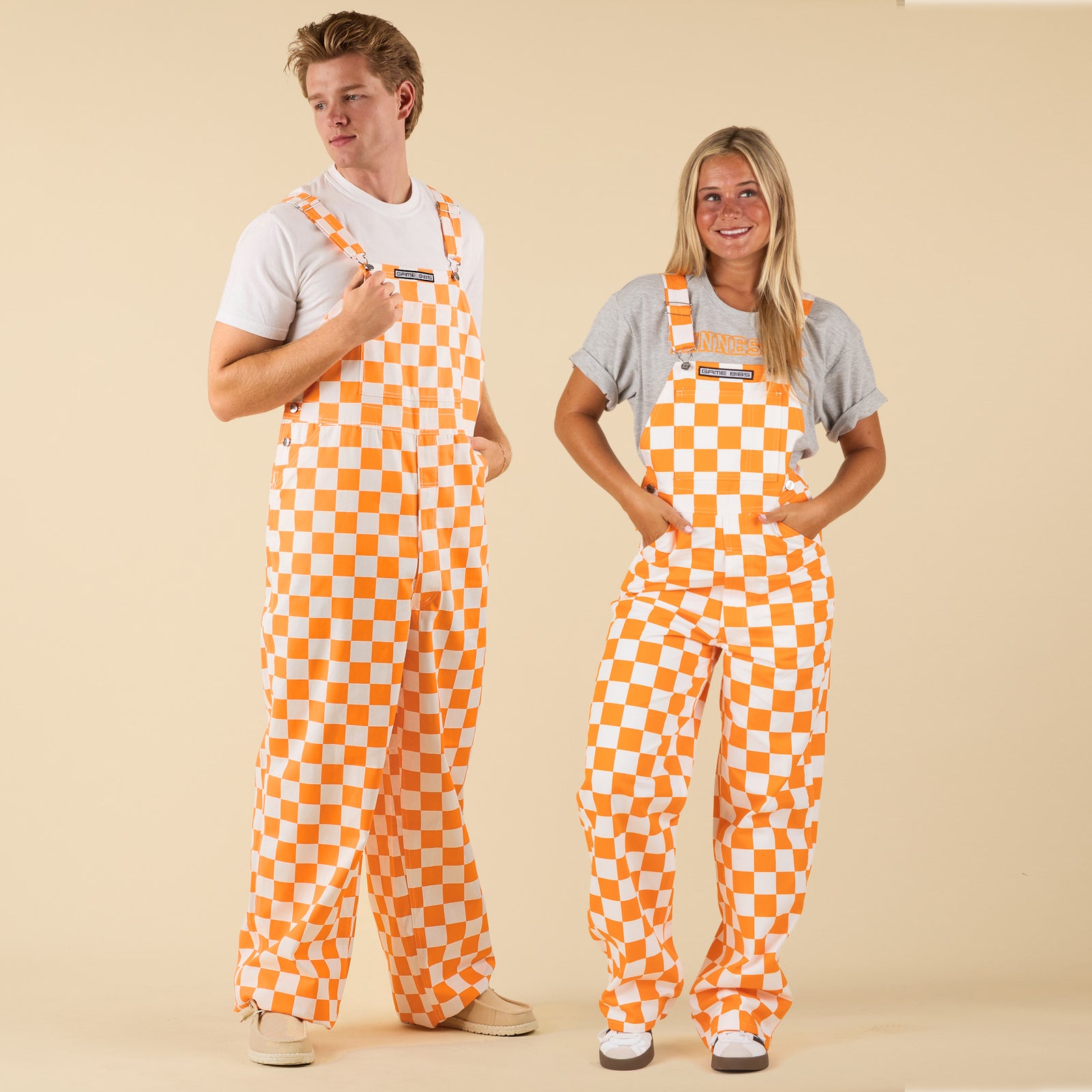 Two people wearing orange and white checkered overalls on a beige background