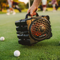 Someone placing a turltebox speaker on a putting green.