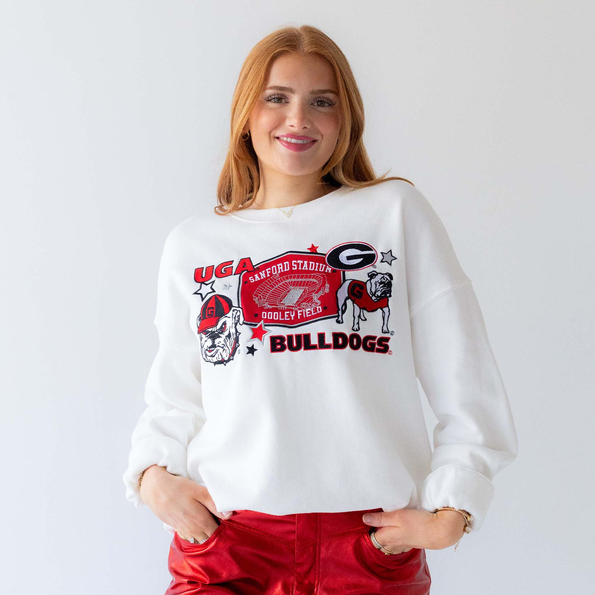 Woman wearing white University of Georgia Bulldogs crewneck sweatshirt with stadium and mascot graphic.