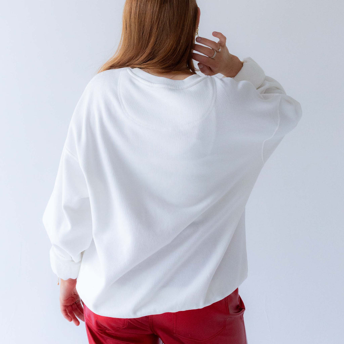 Woman wearing plain white University of Georgia crewneck sweatshirt with no design.