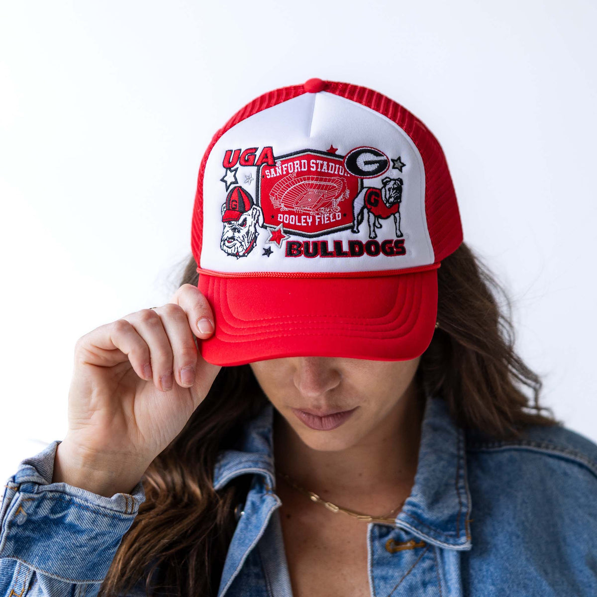 Woman wearing red and white University of Georgia Bulldogs trucker hat with embroidered Sanford Stadium and mascot patch.