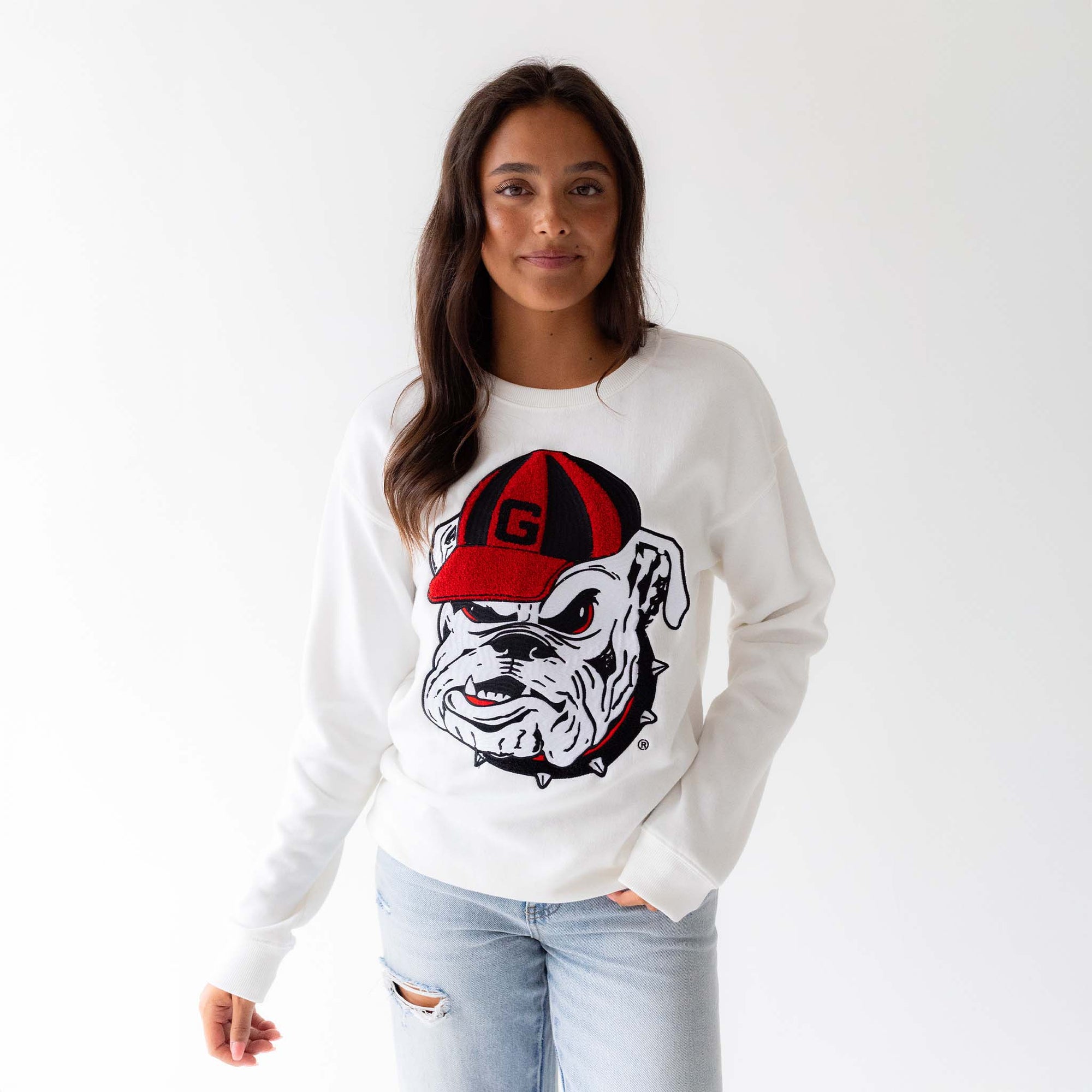 Woman wearing white University of Georgia crewneck sweatshirt with oversized Bulldog mascot graphic in red and black.
