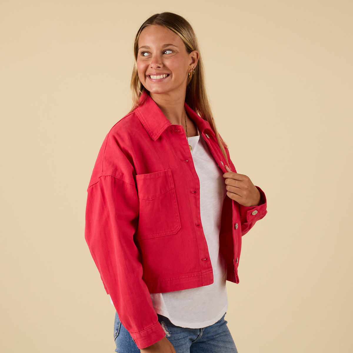 Woman wearing a red jacket over a white shirt on a beige background