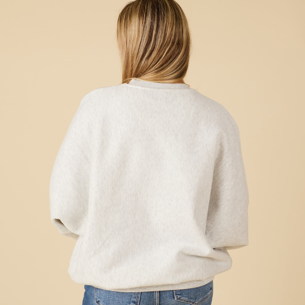 Person wearing a light gray sweatshirt against a beige background