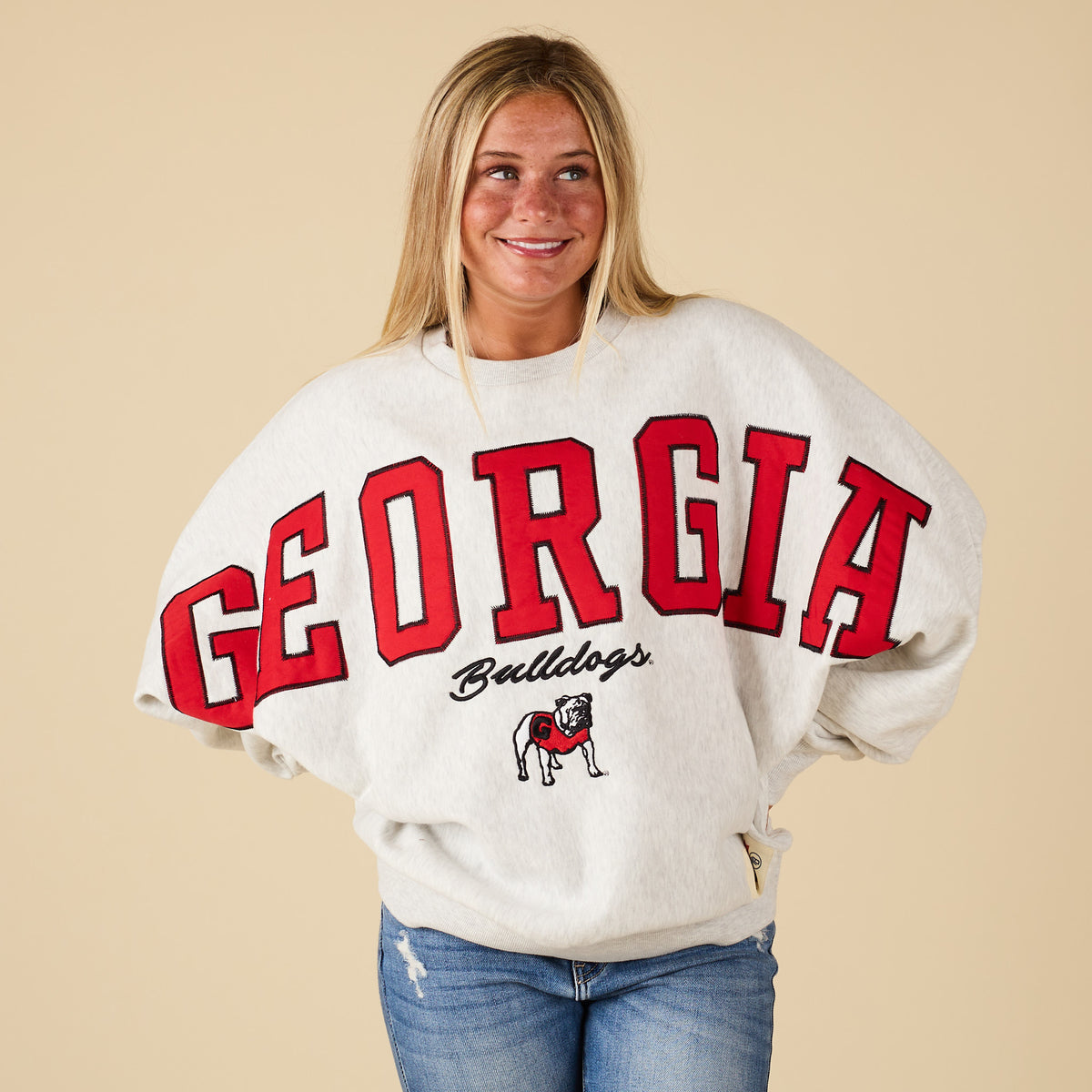 Person wearing a Georgia Bulldogs sweatshirt on a beige background