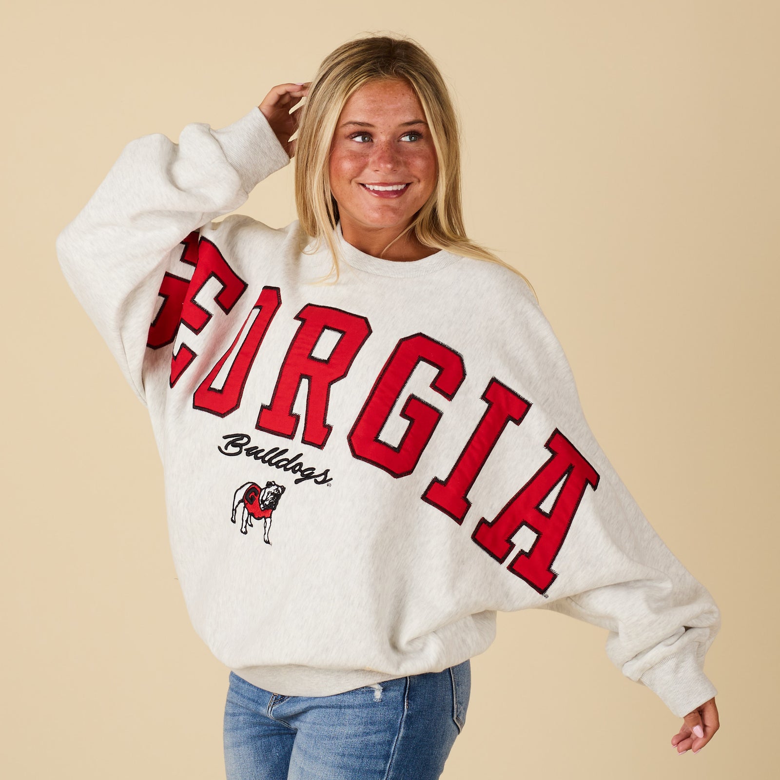 Person wearing a white sweater with 'Georgia Bulldogs' text on a beige background