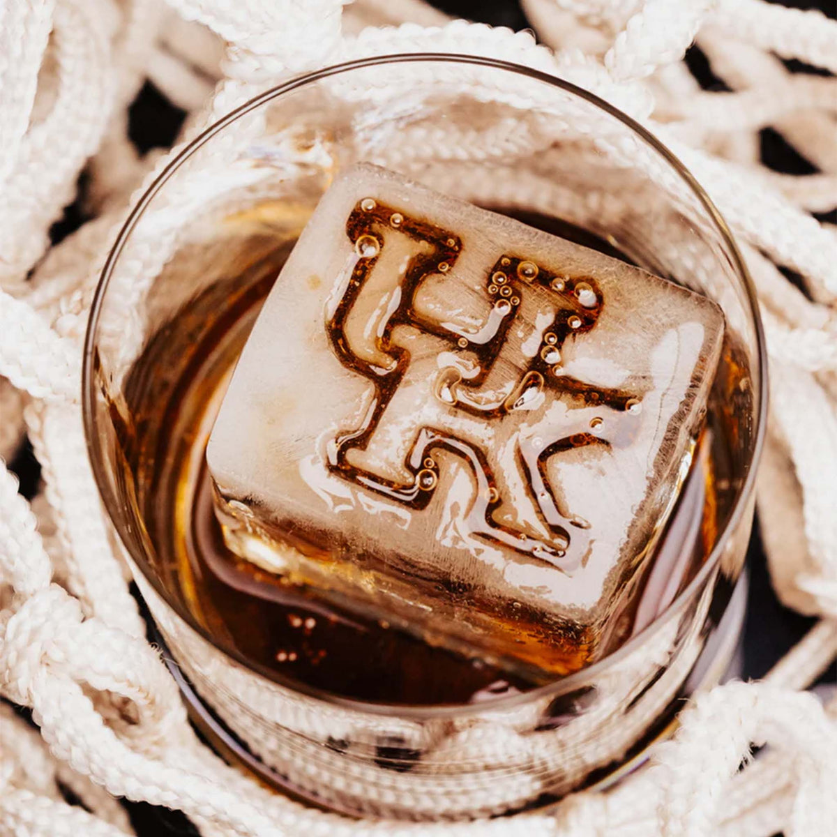 Drink glass with UK-shaped ice cube resting on basketball net background
