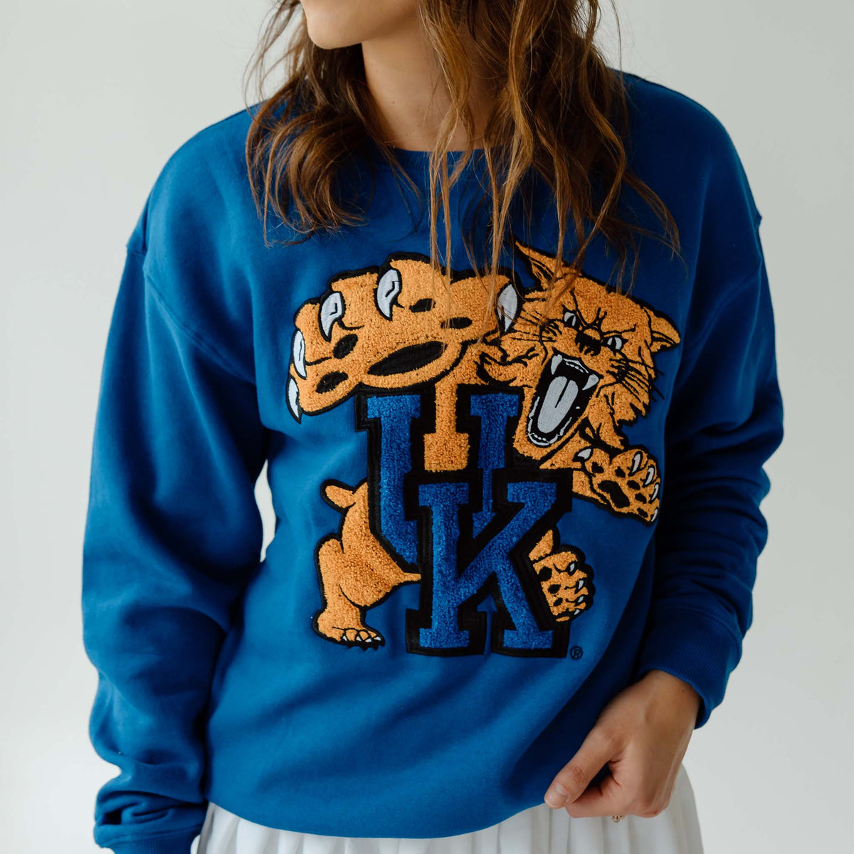 Close-up of royal blue crewneck sweatshirt showing oversized Kentucky Wildcats chenille patch logo.