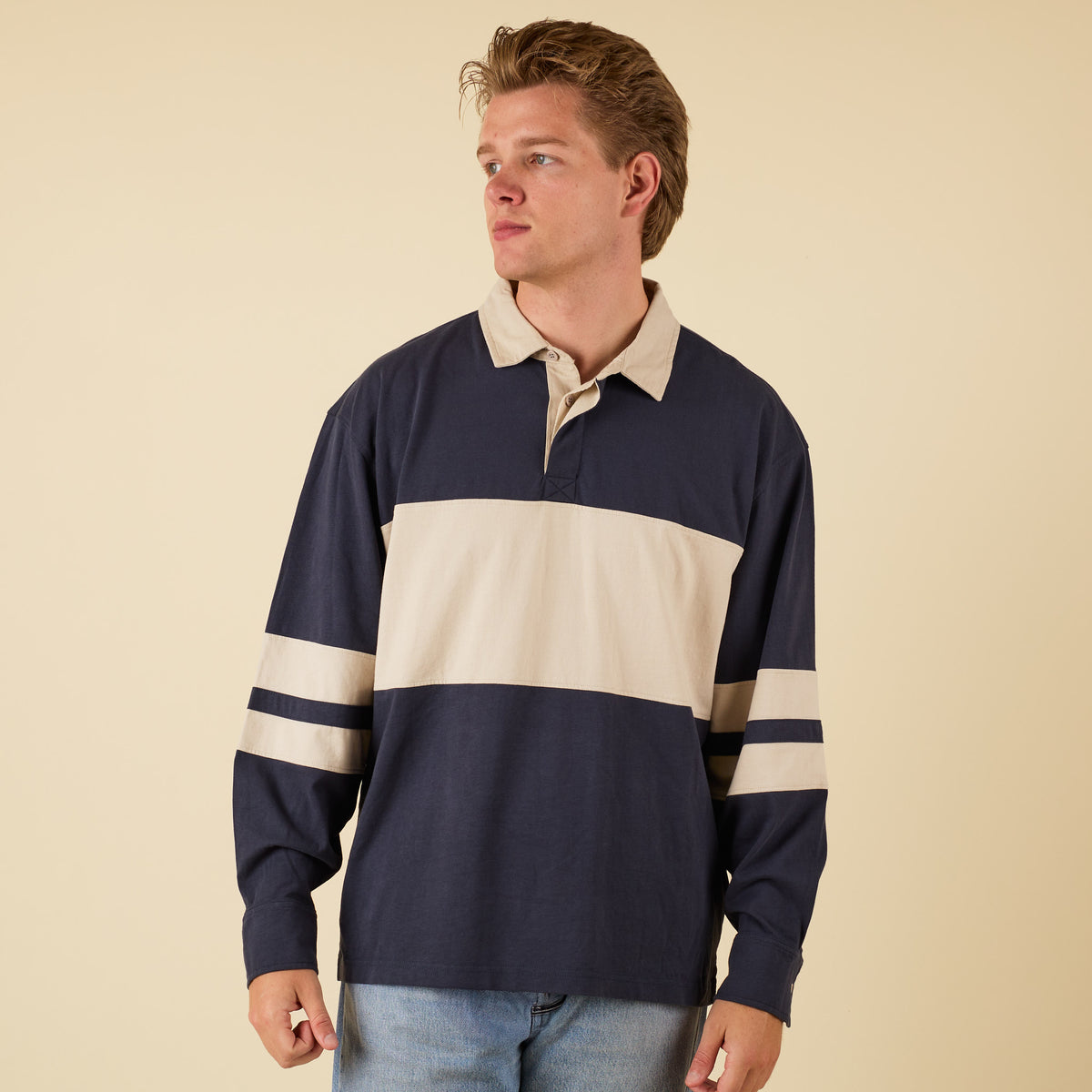 Man wearing a navy and beige oversized rugby shirt
