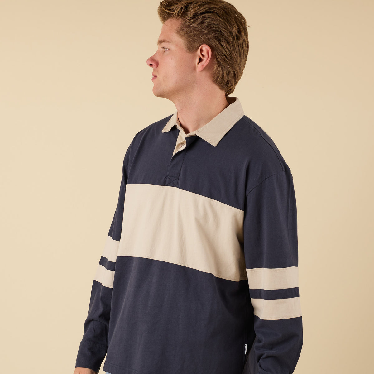 Man wearing a navy and beige oversized rugby shirt
