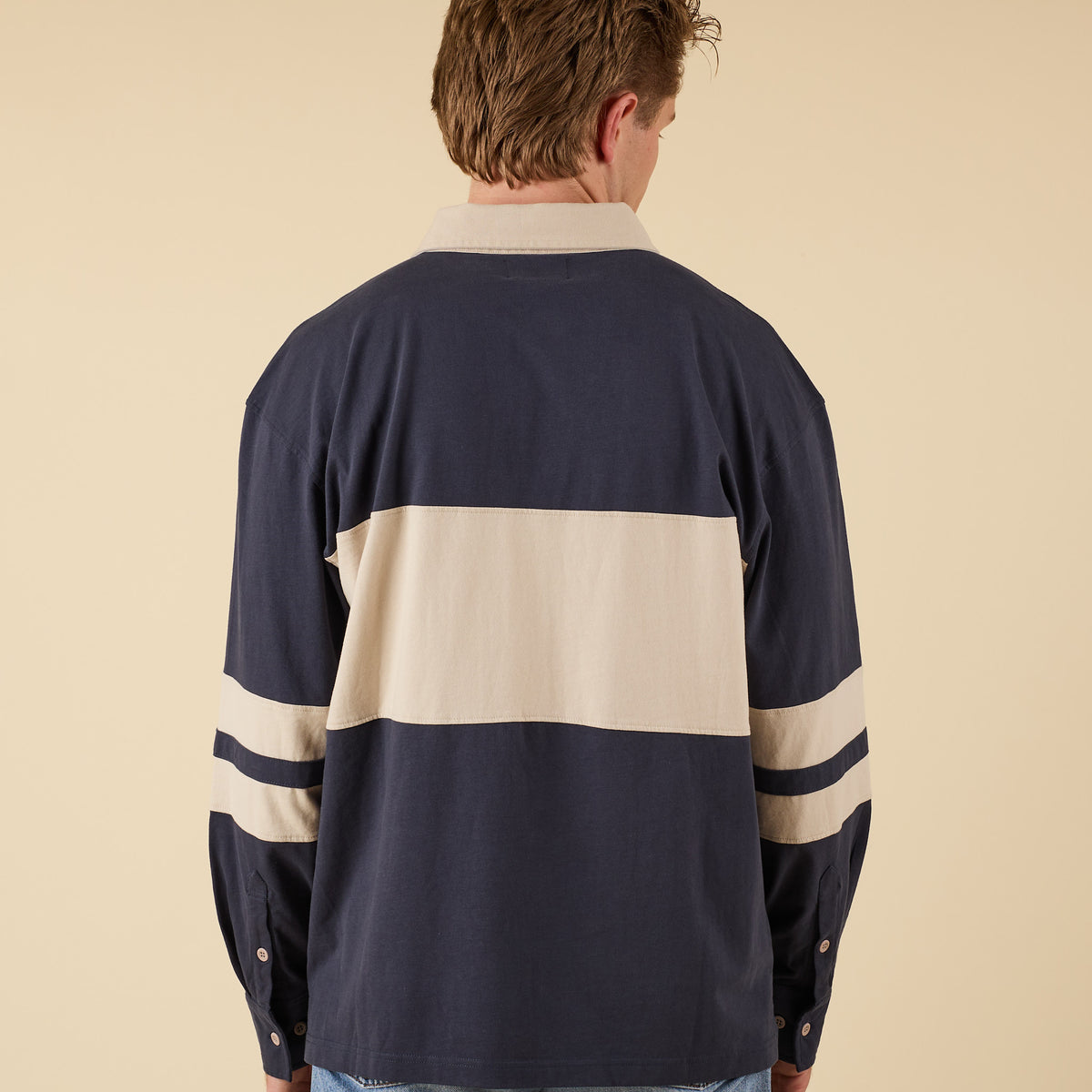 Man wearing a navy and beige oversized rugby shirt
