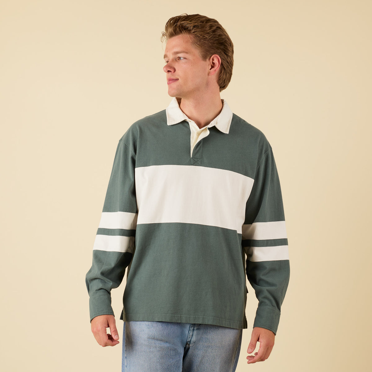 Man wearing a green rugby shirt with white stripes on a beige background
