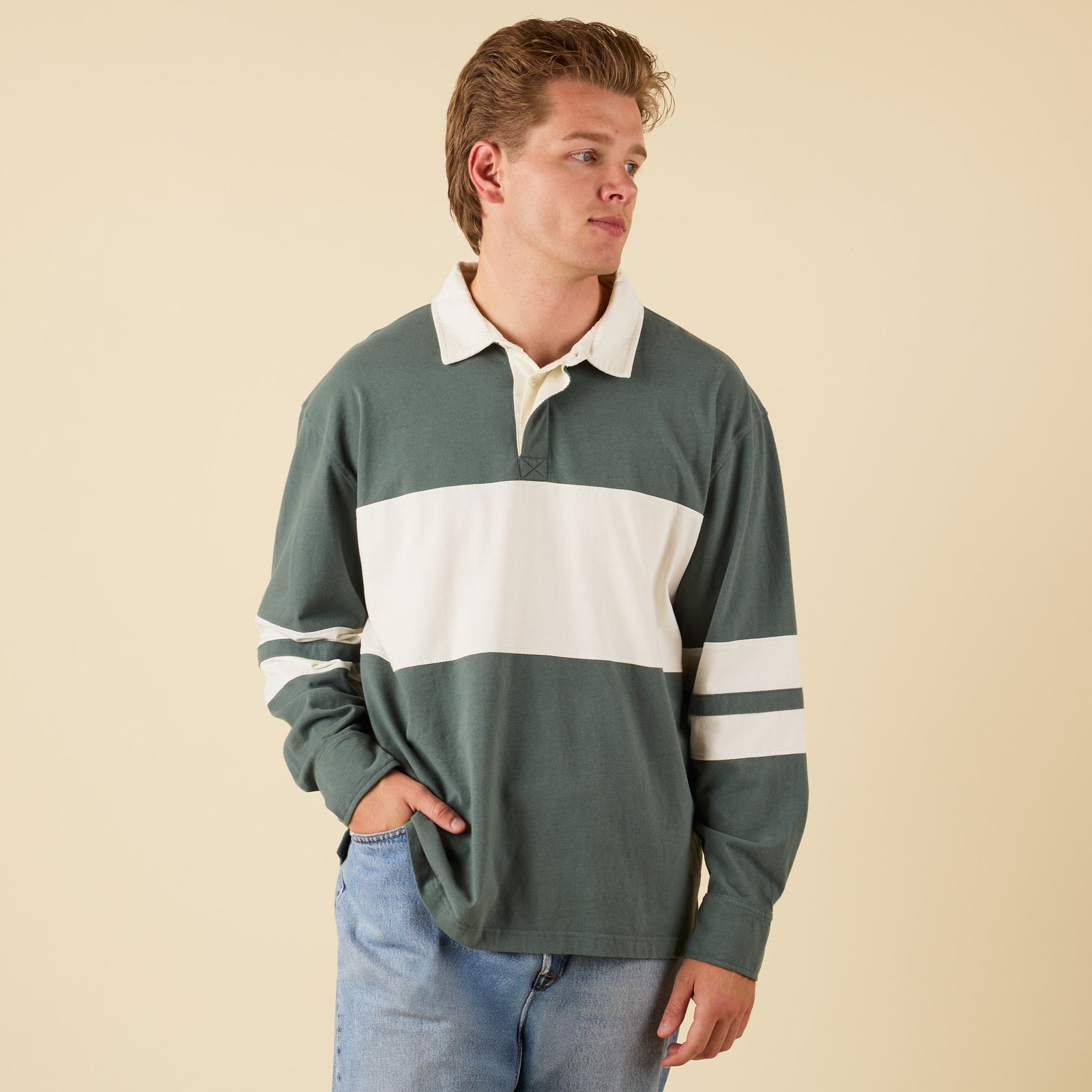 Man wearing a green and white striped rugby shirt against a beige background