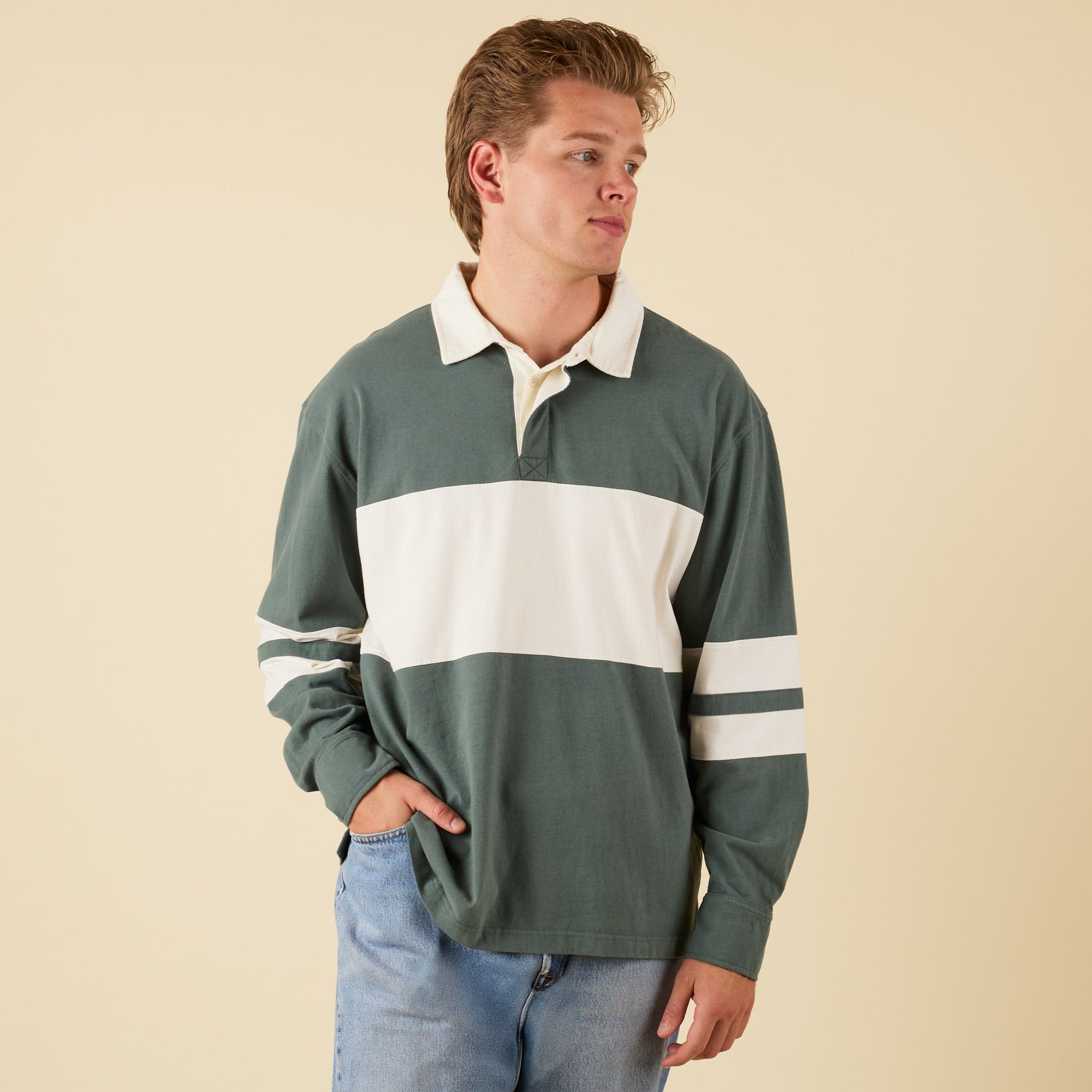 Man wearing a green and white striped rugby shirt against a beige background