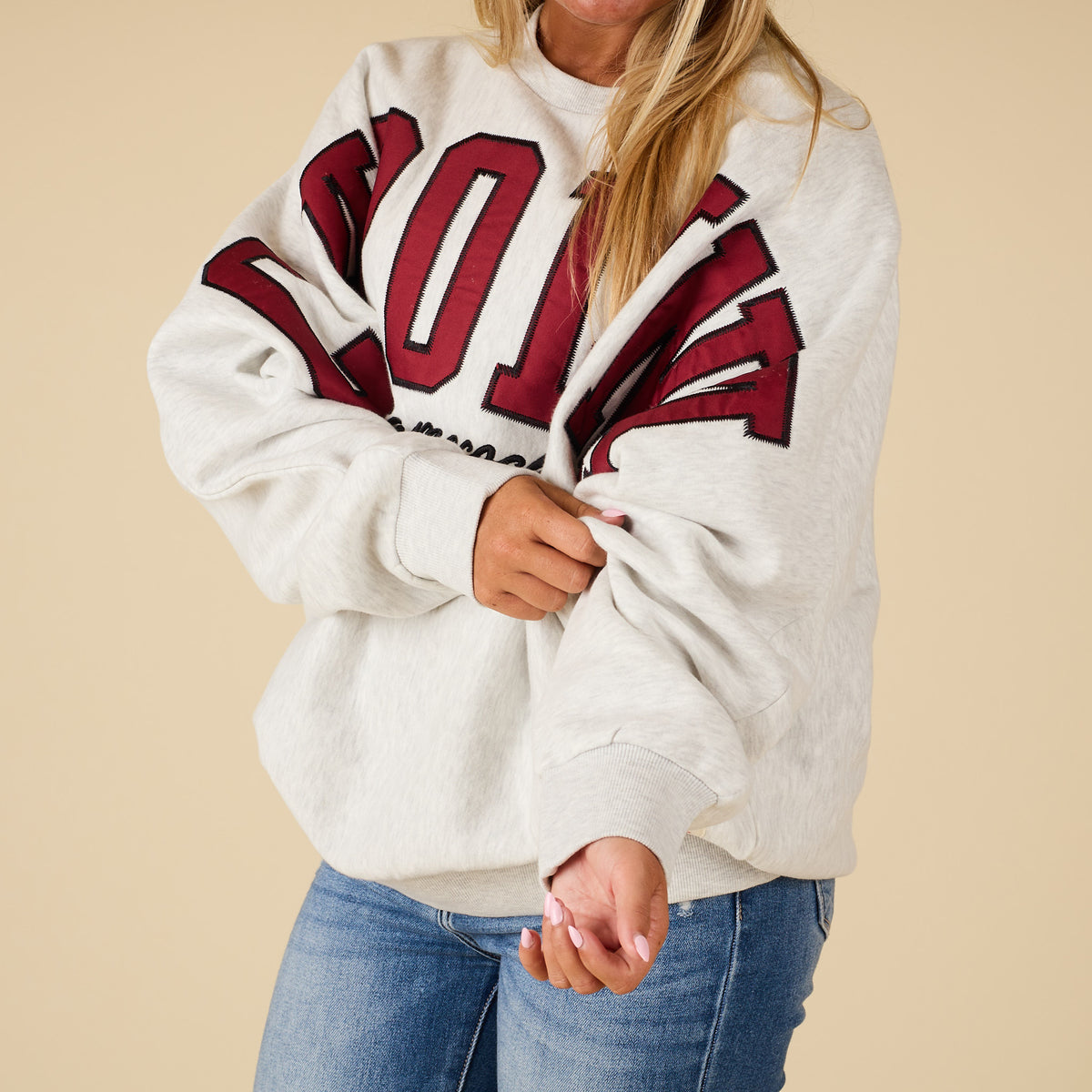 Person wearing a white sweatshirt with red lettering on a beige background