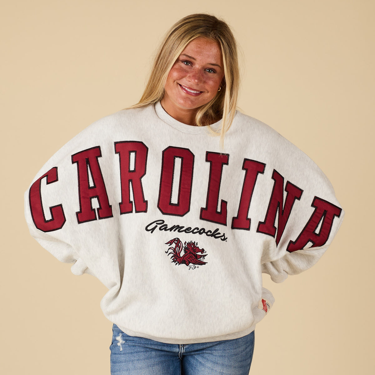 Person wearing a 'Carolina Gamecocks' sweatshirt on a beige background