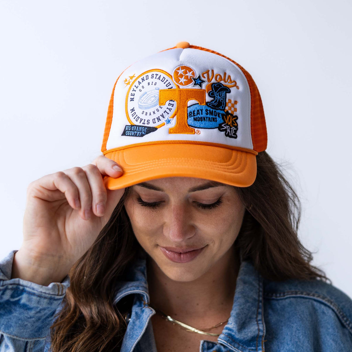 Woman wearing orange and white Tennessee Volunteers trucker hat with embroidered Neyland Stadium, Smokey, and Power T graphics.