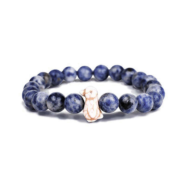 The Fahlo Passage Penguin Bracelet in Igloo Blue. Beaded bracelet with round, marbled blue stones and a small penguin-shaped bead in the center, displayed on a white background.