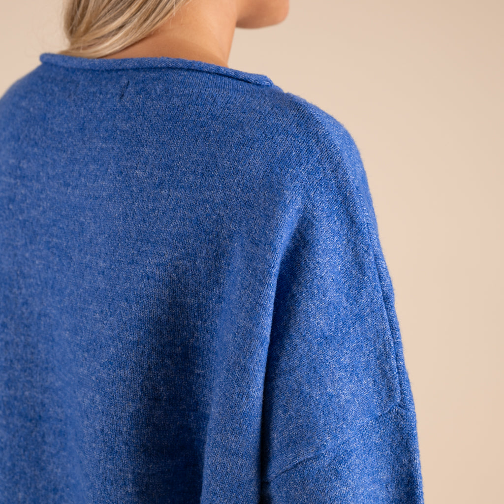 Blue sweater worn by a person on a beige background