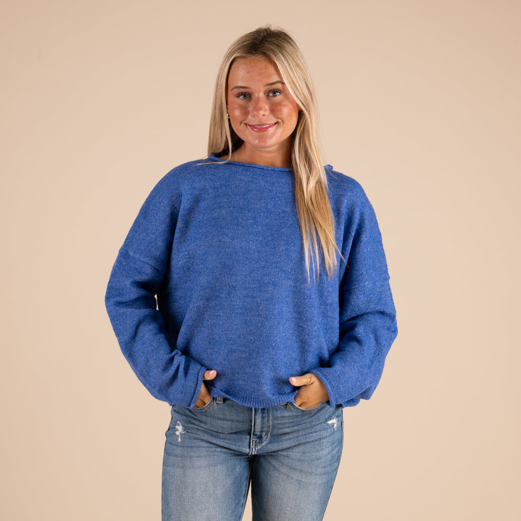 Woman wearing a blue sweater and jeans against a beige background
