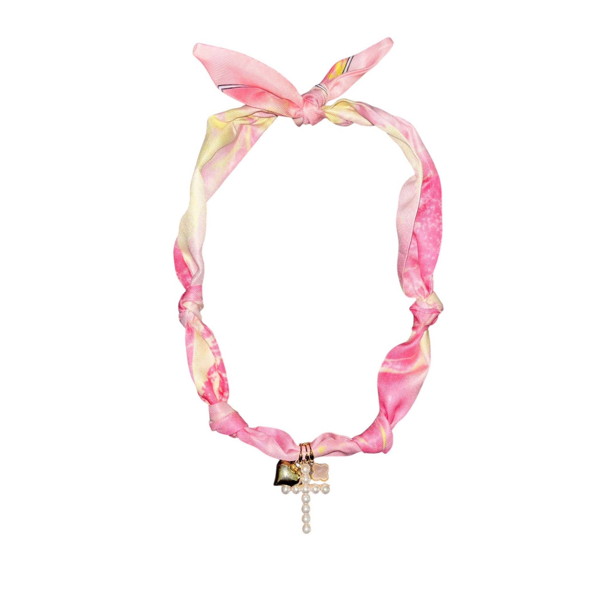 Pink and yellow marbled knotted fabric necklace with gold-tone heart, pearl cross pendant, and small clover charm.