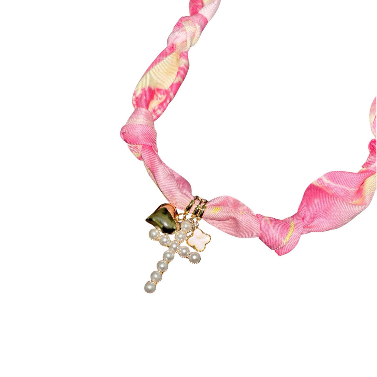 Pink and yellow marbled knotted fabric necklace with gold-tone heart, pearl cross pendant, and small clover charm.