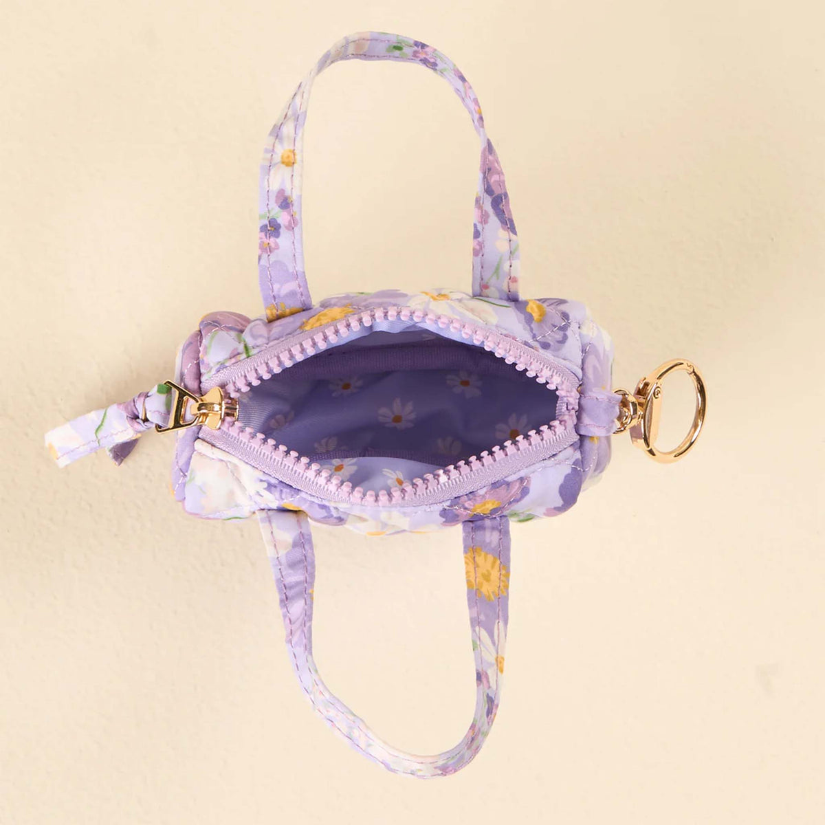 Top view of a purple floral mini duffle keychain bag with zipper open, showing matching floral interior.
