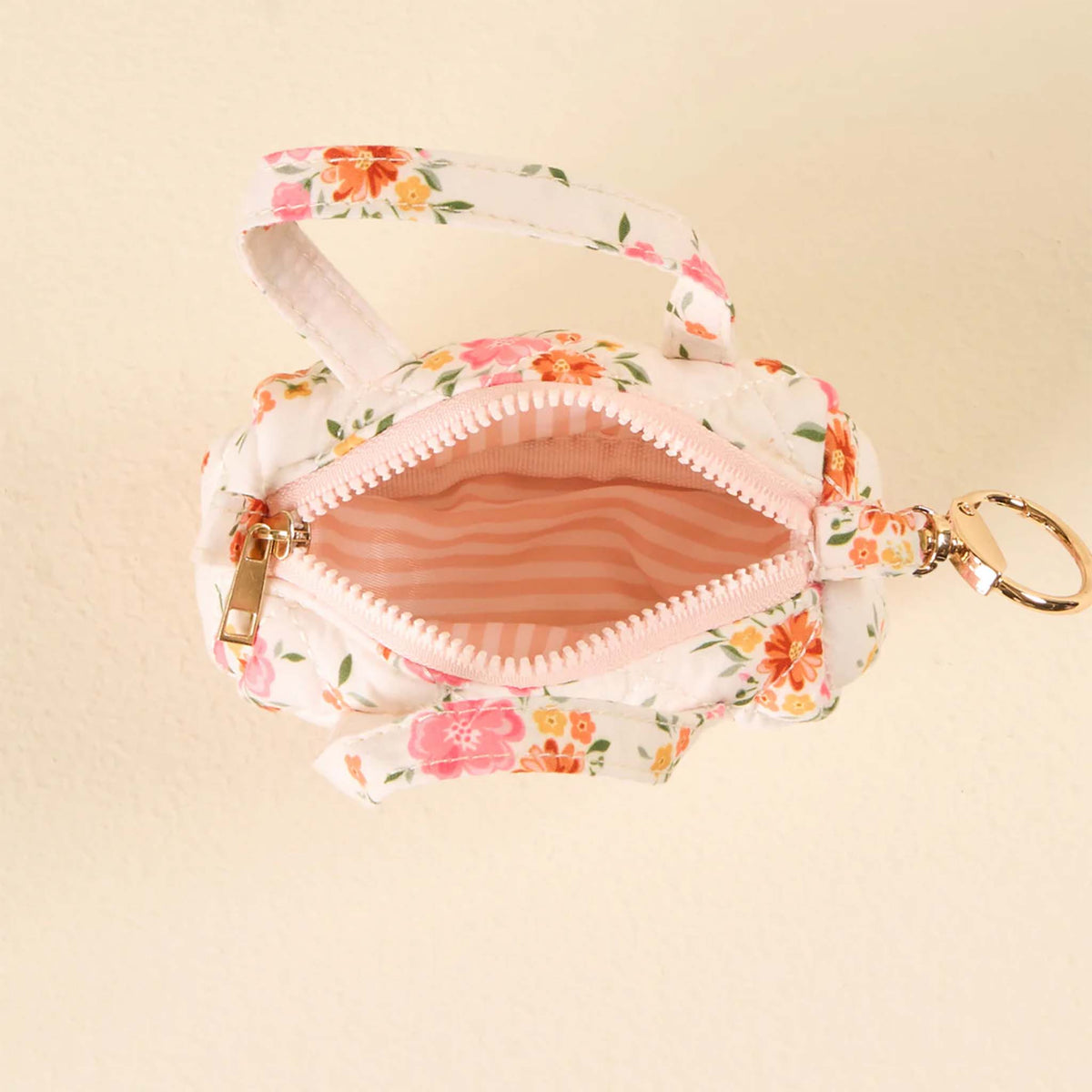 Top view of the white floral mini duffle keychain with zipper open, showing pink striped interior lining.