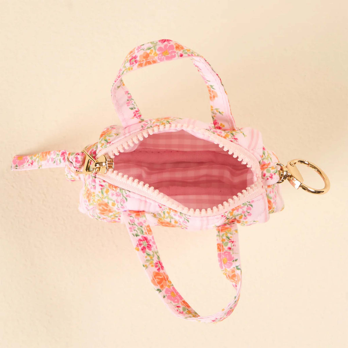 Top view of pink floral mini duffle keychain with zipper open, showing pink gingham interior.