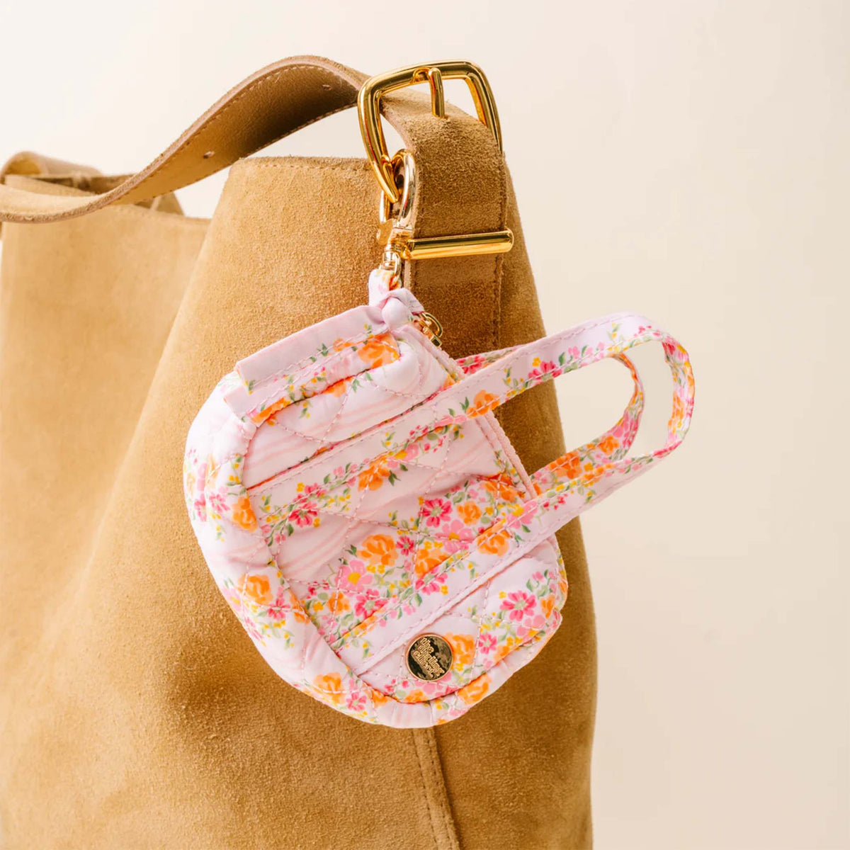 Mini floral keychain clipped to a tan suede tote bag using gold keyring clip.