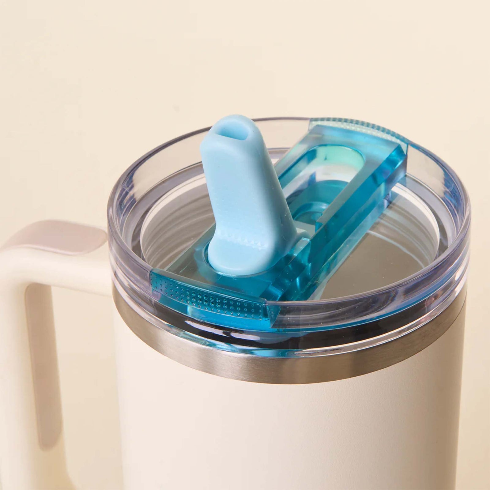 Close-up of blue flip straw lid attached to a white tumbler, shown with the straw flipped open.