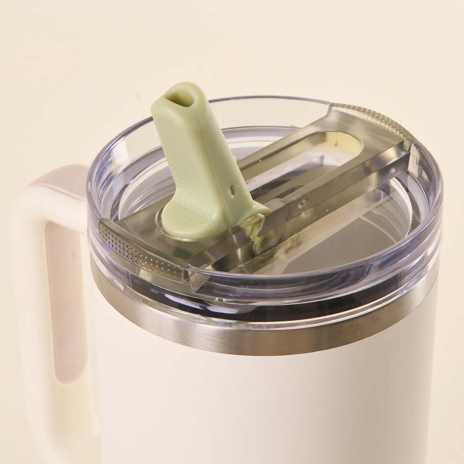 Close-up of sage green flip straw lid on a white tumbler with the straw spout flipped open.