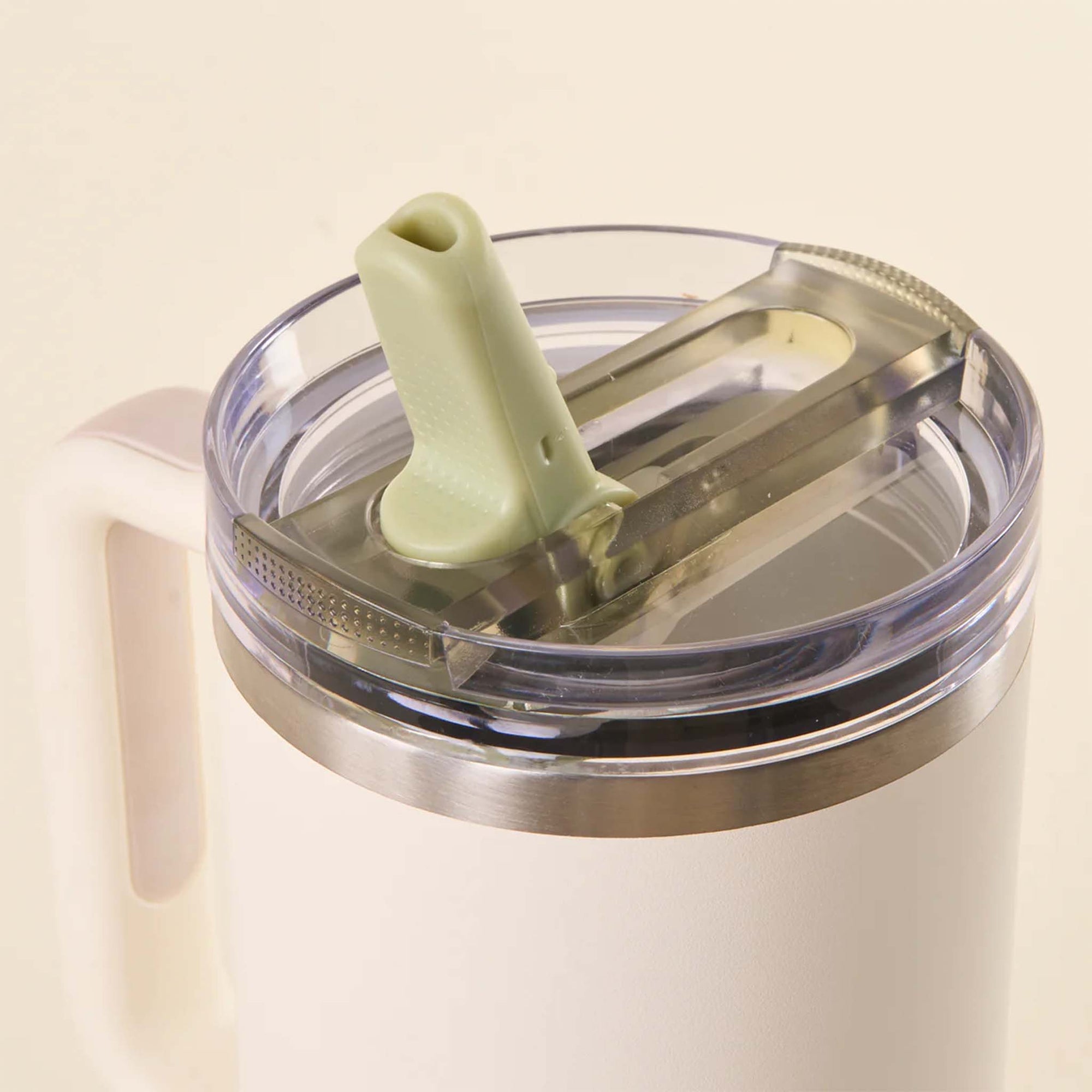 Close-up of sage green flip straw lid on a white tumbler with the straw spout flipped open.