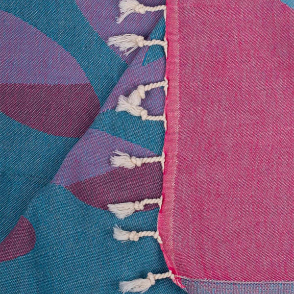 Close-up of a colorful fabric with blue, purple, and pink hues and white tassels.