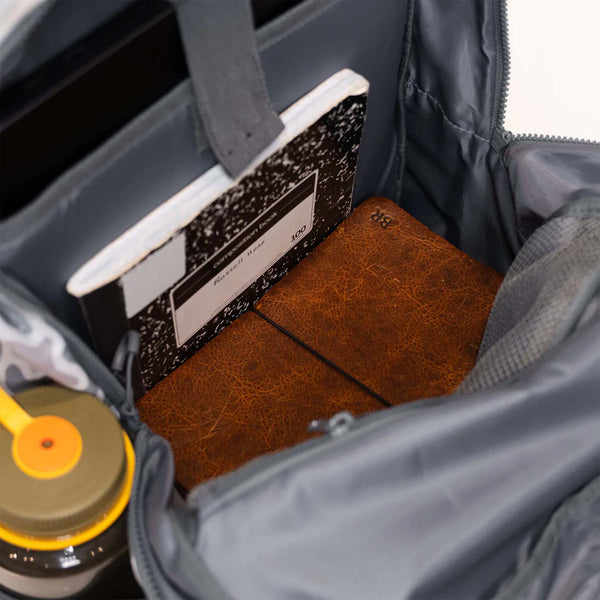 Notebooks shown inside of a grey backpack.