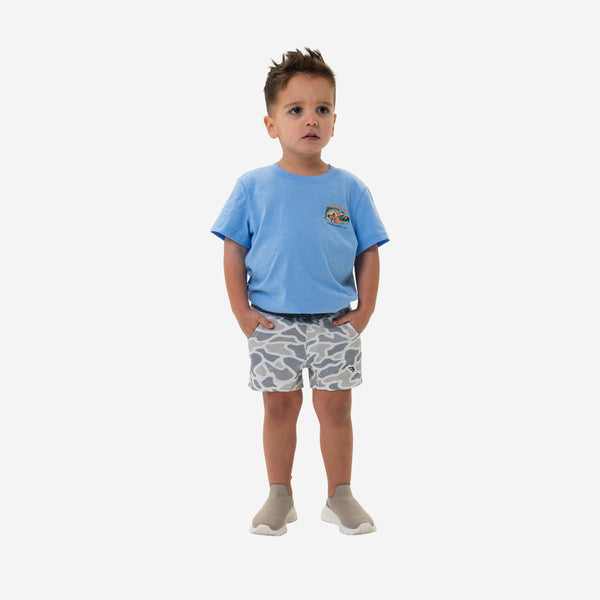 Child wearing a blue shirt and Burlebo Youth Athletic Shorts in White Camo in front of a white background.